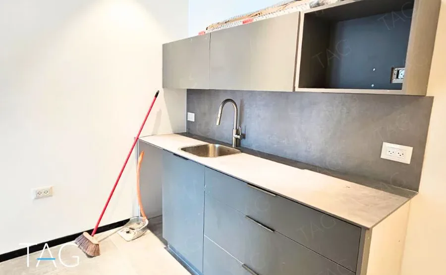 מטבחון בACRO BUSINESS CAMPUS עם ארונות אפורים כהים וחיפוי קיר תואם - תג נכסים