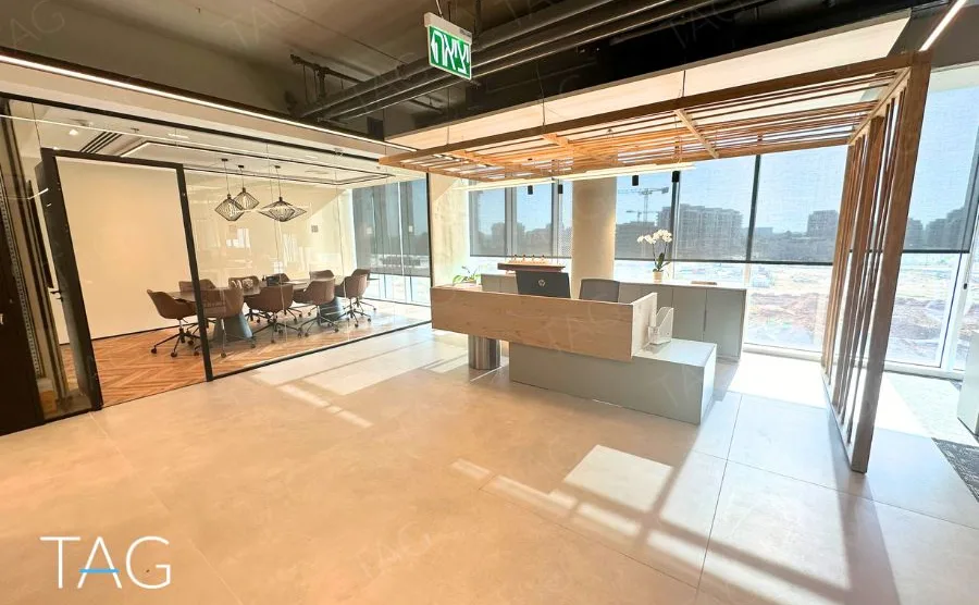 אזור קבלה בACRO BUSINESS CAMPUS עם דלפק עץ, תקרת סנפירים וחדר ישיבות מזוגג - תג נכסים