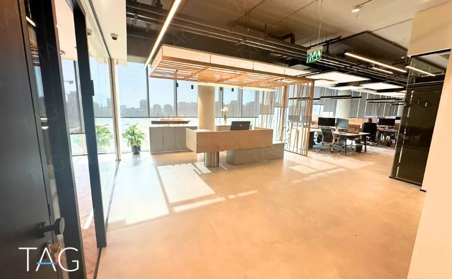אופן ספייס בACRO BUSINESS CAMPUS עם עמדות עבודה, תקרת סנפירי עץ וחלונות רחבים - תג נכסים