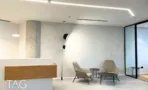 עמדת קבלה בACRO BUSINESS CAMPUS עם דלפק עץ בהיר, קיר טיח מרוח וכורסאות אפורות - תג נכסים