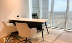 חדר מנהל בACRO BUSINESS CAMPUS עם שולחן עץ, כורסאות ונוף מהחלון הפינתי - תג נכסים