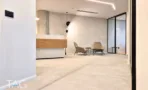 מבואת כניסה בACRO BUSINESS CAMPUS עם דלפק עץ, כורסאות ומחיצת זכוכית שחורה - תג נכסים