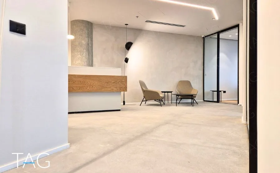 מבואת כניסה בACRO BUSINESS CAMPUS עם דלפק עץ, כורסאות ומחיצת זכוכית שחורה - תג נכסים