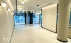 חלל משרדי בACRO BUSINESS CAMPUS עם עמודי בטון עגולים, תאורת קיר וחלונות רחבים - תג נכסים
