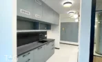 מטבח משרדי בACRO BUSINESS CAMPUS עם ארונות תכולים בהירים ומשטח עבודה כהה - תג נכסים