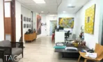 חלל קבלה פתוח במשרד במגדל רוטשילד 3 עם רצפת עץ, עבודות אמנות צבעוניות ועמדות עבודה