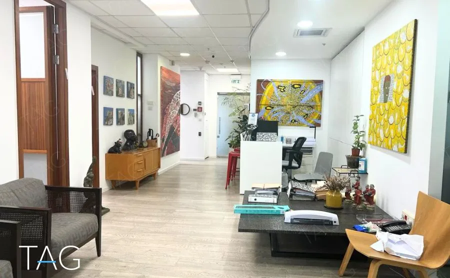 חלל קבלה פתוח במשרד במגדל רוטשילד 3 עם רצפת עץ, עבודות אמנות צבעוניות ועמדות עבודה