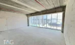 קומת מעטפת בACRO BUSINESS CAMPUS עם קיר אבן, תקרת בטון וחלון רצועה ארוך - תג נכסים