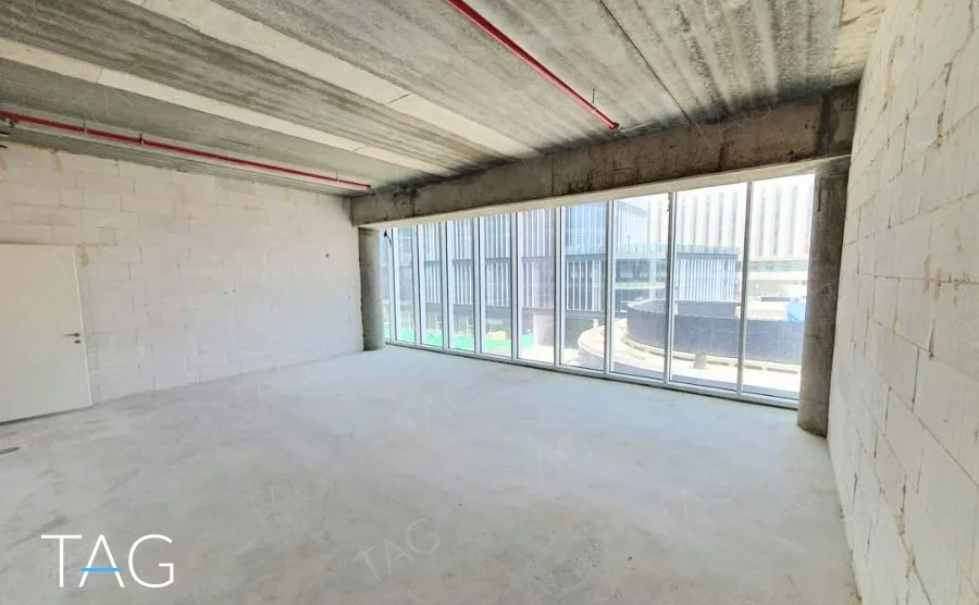 קומת מעטפת בACRO BUSINESS CAMPUS עם קיר אבן, תקרת בטון וחלון רצועה ארוך - תג נכסים