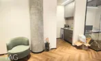 חלל משרדי בACRO BUSINESS CAMPUS עם עמוד בטון גלוי, פרקט אדרה וכורסה ירוקה - תג נכסים