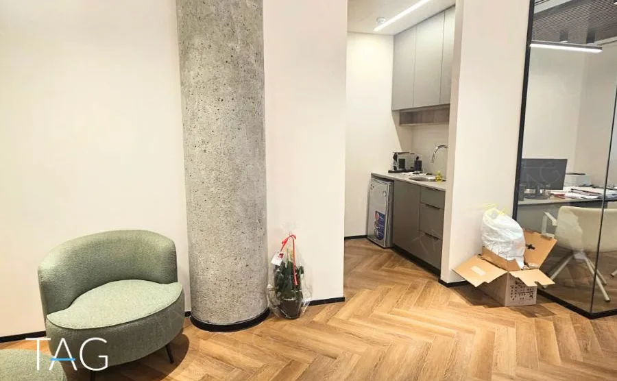 חלל משרדי בACRO BUSINESS CAMPUS עם עמוד בטון גלוי, פרקט אדרה וכורסה ירוקה - תג נכסים