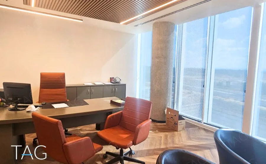 חדר מנהלים בACRO BUSINESS CAMPUS עם שולחן ישיבות, כורסאות כתומות ונוף מהחלון - תג נכסים