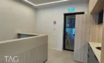 מבואה בACRO BUSINESS CAMPUS עם דלפק מחורץ, ארון עץ ודלת כניסה שחורה - תג נכסים