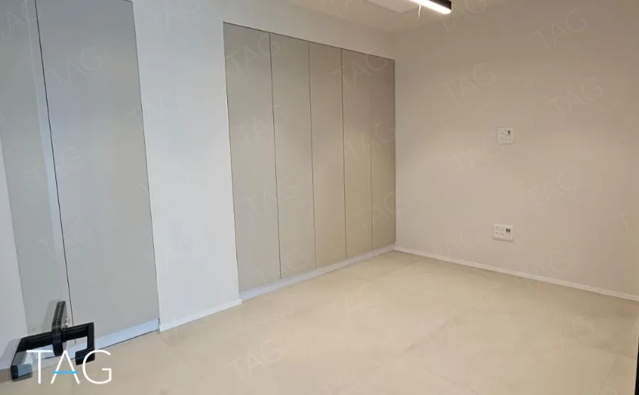חדר בACRO BUSINESS CAMPUS עם ארונות מובנים לבנים ורצפת אריחים בהירה - תג נכסים
