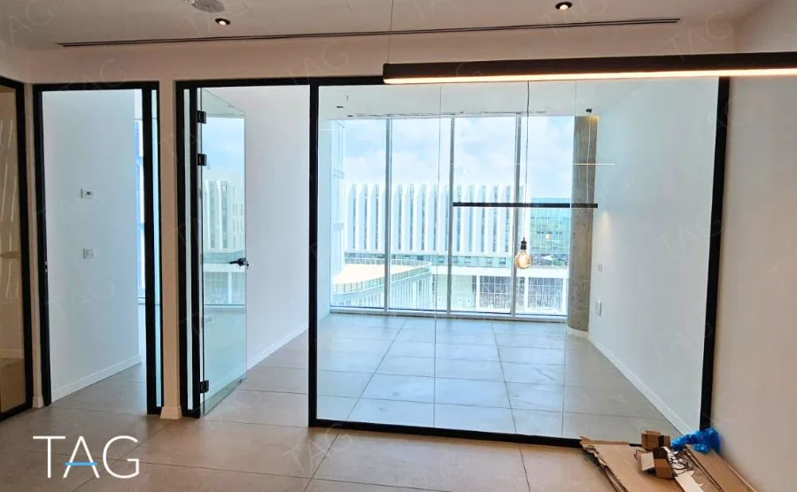 חלל פתוח בACRO BUSINESS CAMPUS עם דלתות זכוכית שחורות ונוף עירוני מהחלון - תג נכסים