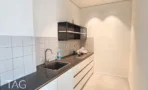 מטבחון בACRO BUSINESS CAMPUS עם ארונות לבנים, חיפוי קרמיקה ומשטח כהה - תג נכסים
