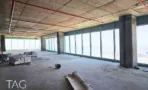 קומה במגדל אלייד סיטי עם חלונות היקפיים, רצפת בטון וחומרי בנייה שנותרו בחלל