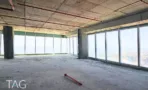 קומת משרדים במגדל אלייד סיטי במצב מעטפת, עם חזית זכוכית ותקרת בטון גלויה