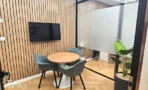 משרד להשכרה 180 מ״ר במגדל אלון תל אביב, חדר ישיבות קטן עם שולחן עגול ומסך על קיר עץ