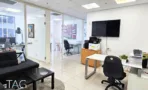 משרד להשכרה 180 מ״ר במגדלי אלון, חלל משרדי עם פינת ישיבה, עמדת עבודה ומסך על הקיר