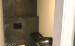 חדר שירותים עם קירות בטון וכיור שחור