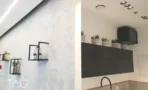 מטבחון עם צמחייה על מדפים, קיר בטון ומסך תלוי