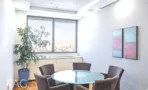 חדר פגישות קטן עם שולחן זכוכית עגול וחלון לנוף העיר במגדל על