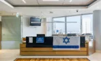 עמדת קבלה מחופה עץ עם מסך תלוי ובמת עץ בכניסה למשרד במגדל על
