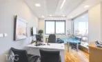 חדר מנהל עם שולחן עבודה ופינת ישיבה מול חלונות פינתיים לנוף תל אביב