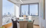 פינת ישיבה בחדר פינתי עם חלונות רצופים ונוף לקו הרקיע של תל אביב