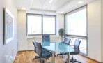 חדר ישיבות עם שולחן זכוכית וכיסאות משרד שחורים מול חלונות פינתיים במגדל על