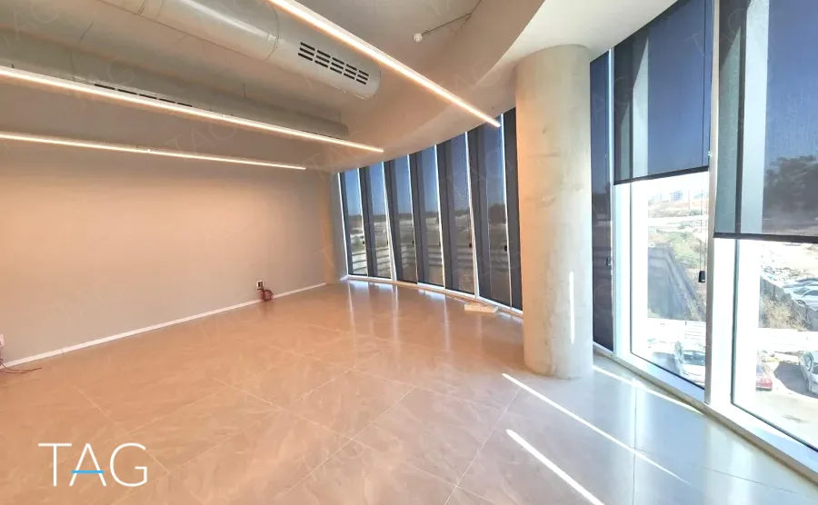 חלל משרדי בACRO BUSINESS CAMPUS עם עמוד עגול, חלונות רצועה ותאורה ליניארית - תג נכסים