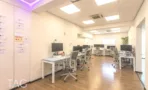 שורת עמדות עבודה לבנות על פרקט בהיר במשרד להשכרה באזור רוטשילד בתל אביב