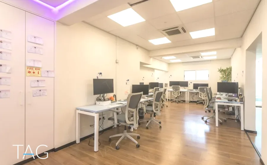 שורת עמדות עבודה לבנות על פרקט בהיר במשרד להשכרה באזור רוטשילד בתל אביב