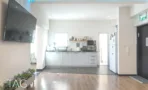 מטבחון עם ארונות לבנים ומסך תלוי במשרד להשכרה באזור רוטשילד בתל אביב
