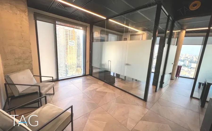 פינת המתנה עם מחיצות זכוכית ועמוד בטון חשוף במשרד 74 מ״ר במגדל רסיטל