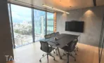 חדר ישיבות עם שולחן כהה, מסך וקיר בטון מול נוף העיר
