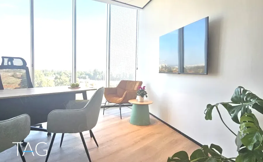 פינת פגישות בACRO BUSINESS CAMPUS עם שולחן, כורסאות מרופדות ונוף מהחלון - תג נכסים
