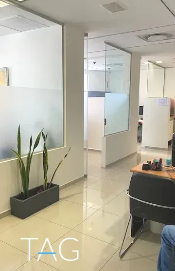מסדרון משרד עם מחיצת זכוכית חלבית וריצוף בהיר, במשרד להשכרה 173 מ