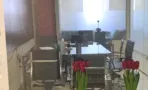 חדר ישיבות מאחורי מחיצת זכוכית, עם קונסולה ואגרטל פרחים בחזית, במשרד להשכרה 173 מ