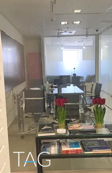 חדר ישיבות מאחורי מחיצת זכוכית, עם קונסולה ואגרטל פרחים בחזית, במשרד להשכרה 173 מ