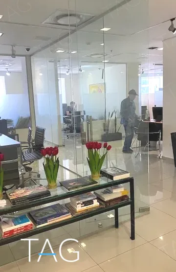 מבט דרך מחיצת זכוכית אל חלל עבודה פתוח, במשרד להשכרה 173 מ