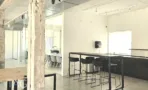 פינת מטבחון במשרד להשכרה בשדרות רוטשילד תל אביב - דלפק שחור, כיסאות בר ושולחן ארוך - תג נכסים