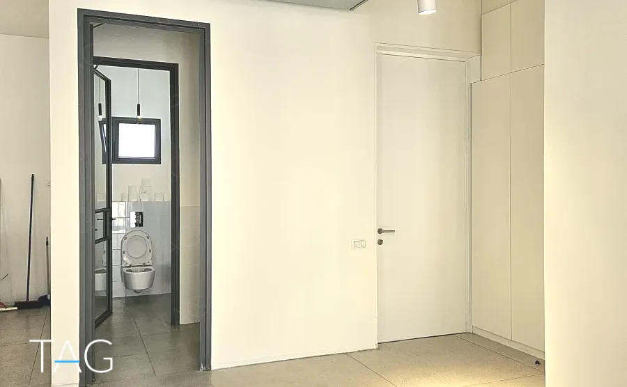 מעבר לשירותים פרטיים במשרד להשכרה בשדרות רוטשילד תל אביב - משקוף שחור וקירות לבנים - תג נכסים
