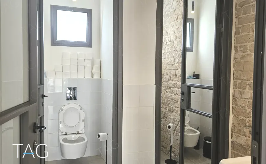 שירותים פרטיים במשרד להשכרה בשדרות רוטשילד תל אביב - חיפוי קרמיקה לבן וקיר לבנים חשוף - תג נכסים