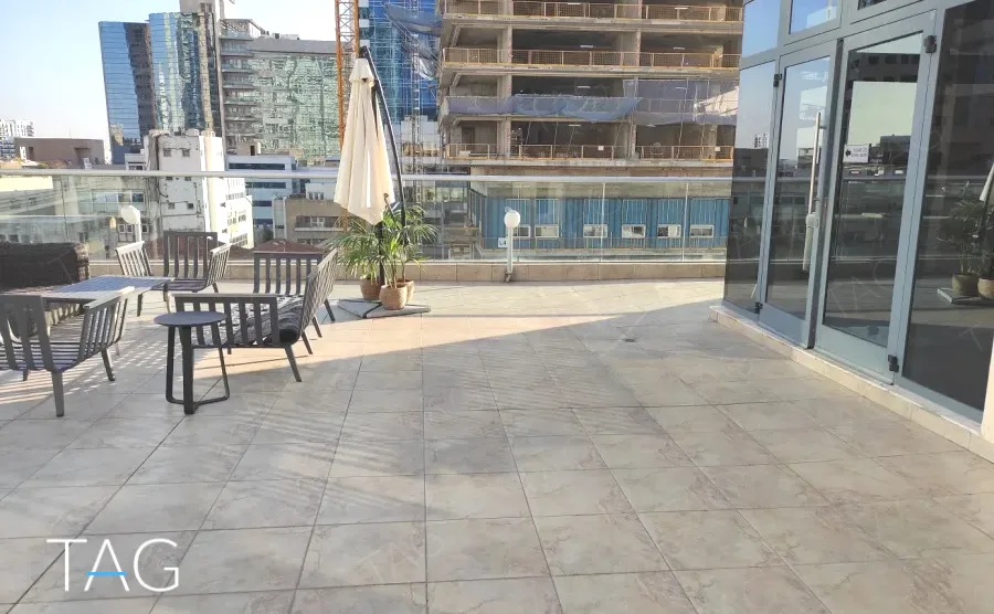 גג פרטי במשרד להשכרה בשדרות רוטשילד תל אביב - ריצוף חוץ אפור, שמשייה ופינת ישיבה - תג נכסים