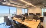 שולחנות עבודה מעץ בהיר לאורך חלונות פנורמיים