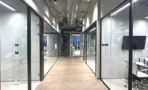 מסדרון עם חדרי זכוכית ורצפת עץ במשרד 347 מ״ר במגדל אקרו