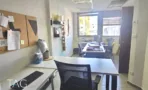 עמדת עבודה במשרד להשכרה בבית לב תל אביב, שולחן לבן וכיסא ארגונומי מול לוח שעם וחלון