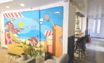 פינת ישיבה משותפת במשרד להשכרה בבית לב תל אביב, ציור קיר צבעוני ובר גבוה לצידו